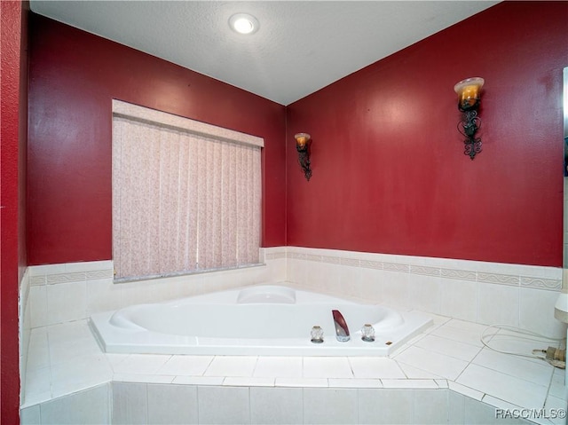 bathroom with tiled bath and a textured ceiling