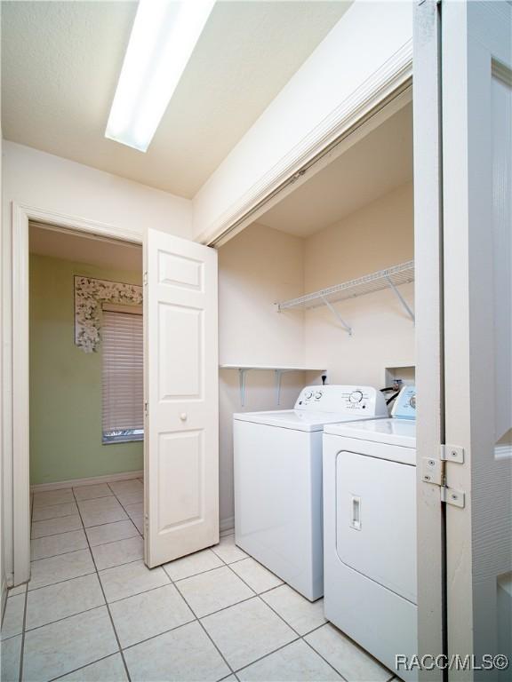 clothes washing area with light tile patterned flooring and washer and dryer