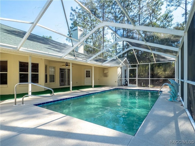 view of swimming pool with ceiling fan, a patio area, and glass enclosure