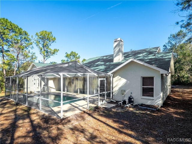 back of house with glass enclosure and a patio area