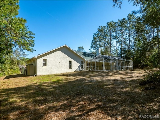 view of side of property with a yard and glass enclosure