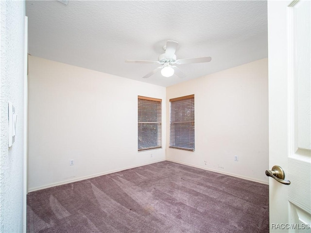 empty room with a textured ceiling, ceiling fan, and dark colored carpet