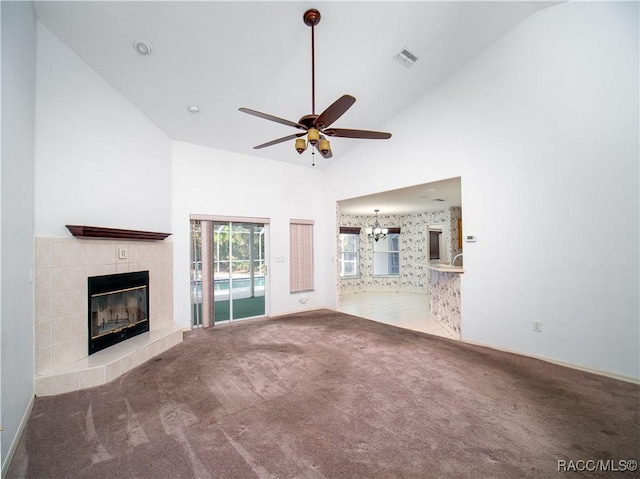 unfurnished living room with high vaulted ceiling, carpet floors, ceiling fan with notable chandelier, and a fireplace