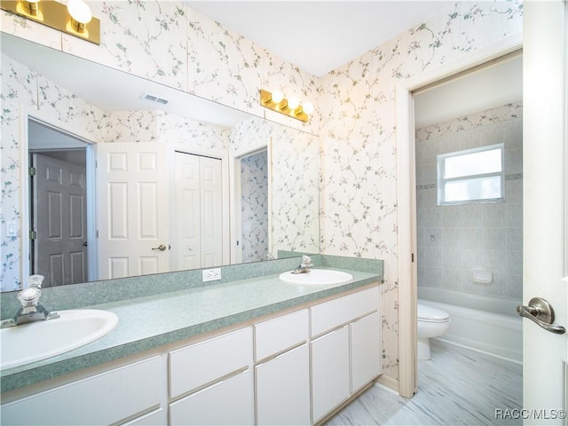 full bathroom featuring tiled shower / bath, vanity, and toilet