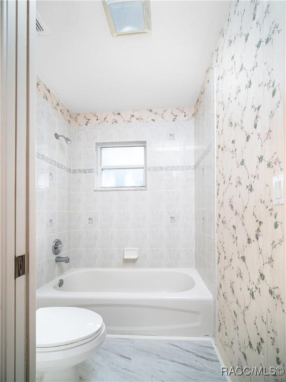 bathroom featuring tiled shower / bath and toilet