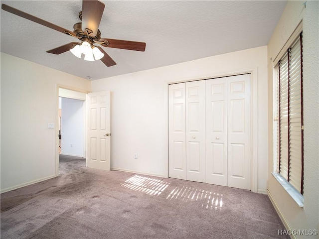 unfurnished bedroom with a textured ceiling, a closet, ceiling fan, and carpet