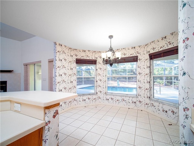 unfurnished dining area with an inviting chandelier, a healthy amount of sunlight, and light tile patterned flooring