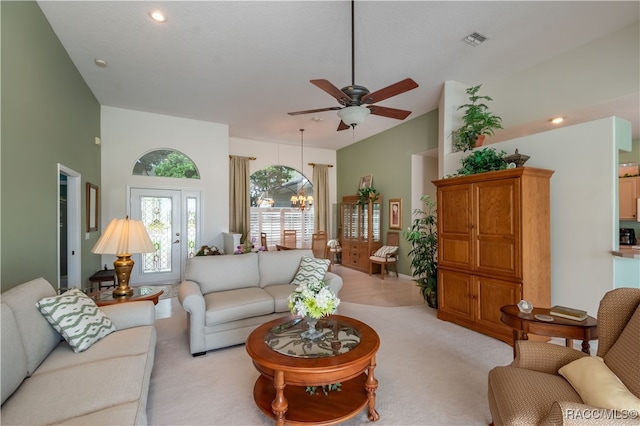 carpeted living room featuring a high ceiling and ceiling fan with notable chandelier