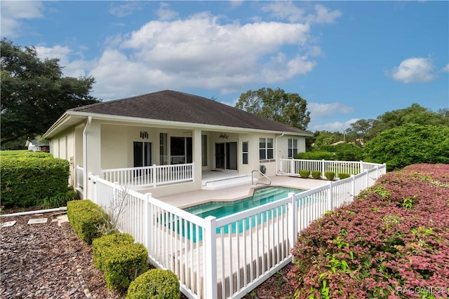 rear view of property featuring a fenced in pool and a patio