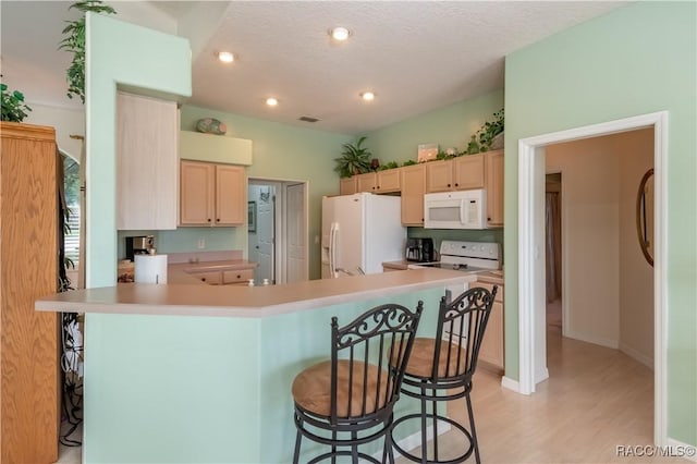 61 E Falconry Ct, Hernando, FL 34442 - kitchen with white appliances, a kitchen bar, light wood-style flooring, light countertops, and light brown cabinetry