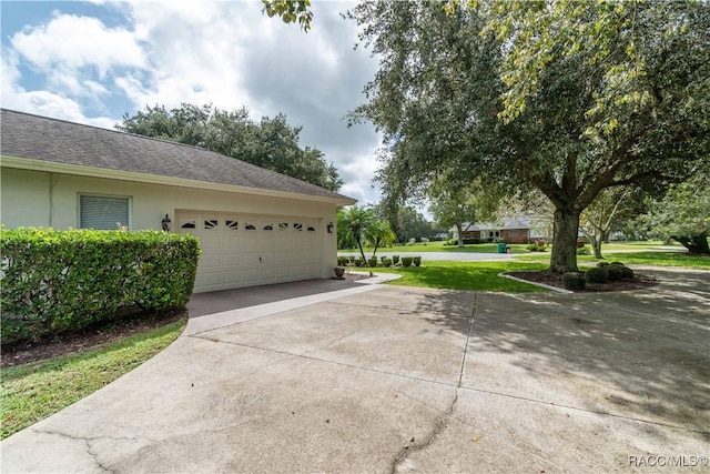 61 E Falconry Ct, Hernando, FL 34442 - view of side of home with concrete driveway, a garage, stucco siding, and a yard