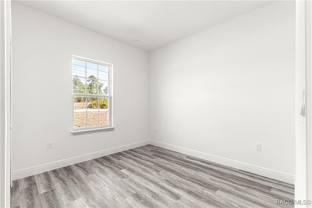 spare room with baseboards and light wood-style floors