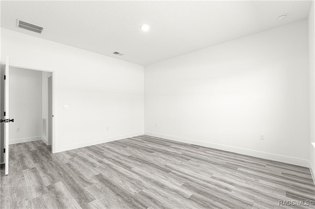 empty room featuring light wood-type flooring, visible vents, and baseboards