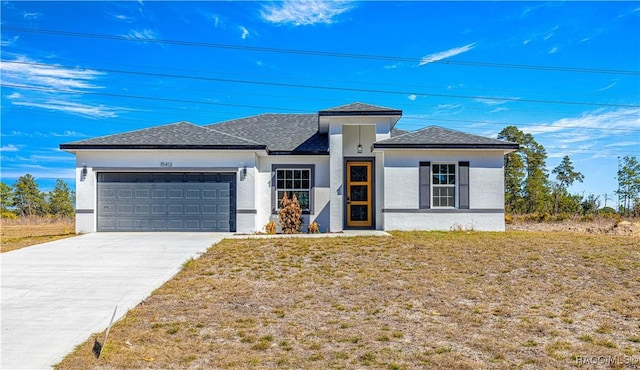 prairie-style home featuring an attached garage, a front lawn, concrete driveway, and stucco siding