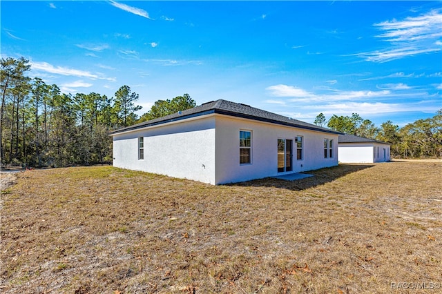 back of house with a lawn and stucco siding