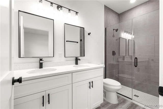 bathroom featuring double vanity, a sink, toilet, and wood finished floors