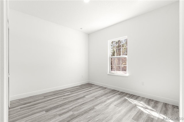 unfurnished room with light wood-type flooring and baseboards