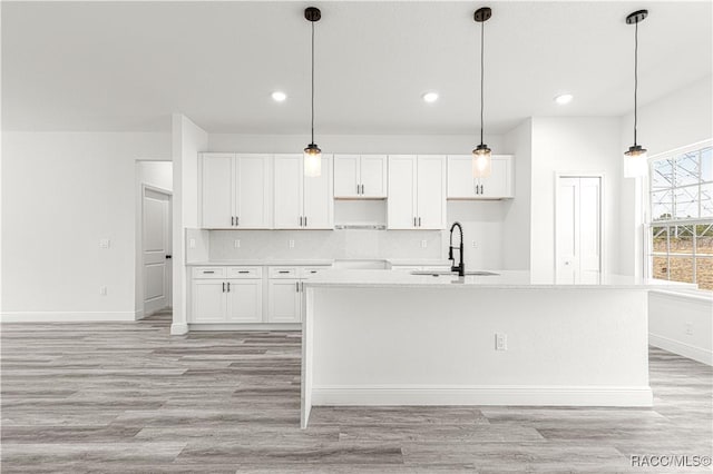 kitchen with pendant lighting, light countertops, an island with sink, and white cabinets