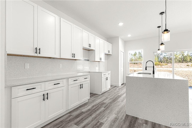 kitchen featuring decorative light fixtures, a sink, backsplash, and white cabinetry