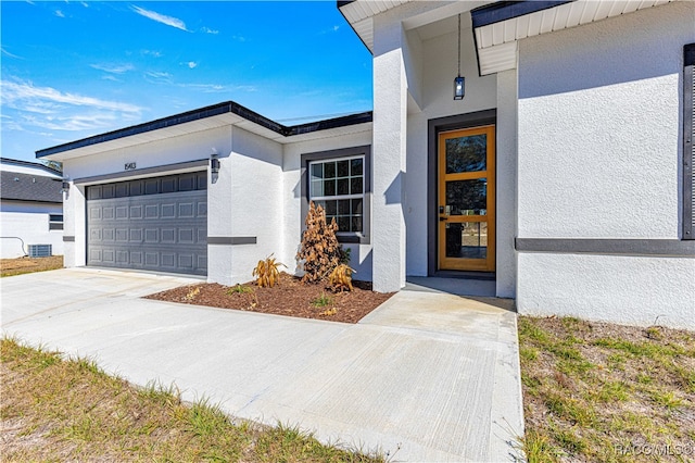 property entrance featuring a garage, driveway, and stucco siding