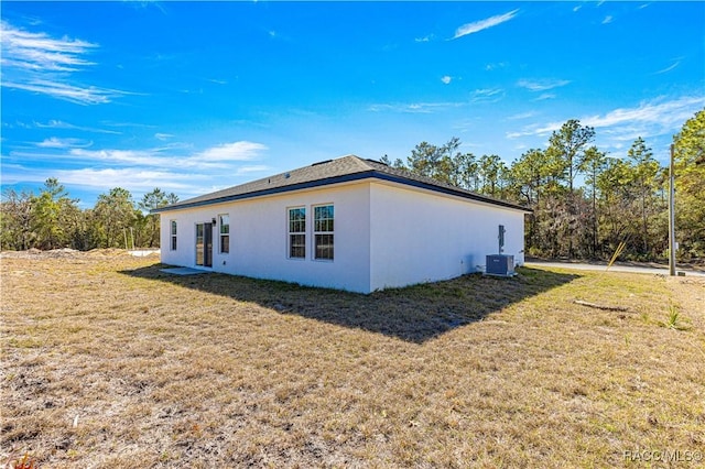 view of property exterior featuring a lawn, central AC unit, and stucco siding