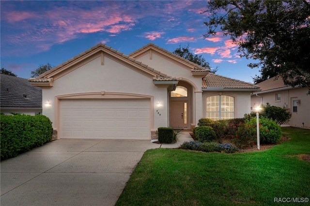 mediterranean / spanish house with a tile roof, an attached garage, driveway, and stucco siding