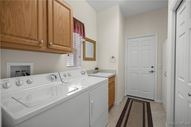 clothes washing area featuring cabinets, sink, washer and dryer, and light tile patterned floors