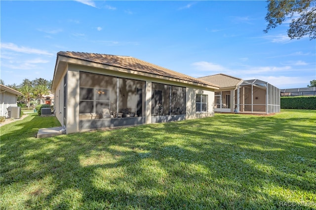 rear view of property with a lawn, glass enclosure, and central AC