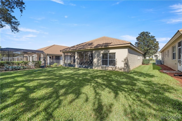 rear view of property featuring central AC and a lawn