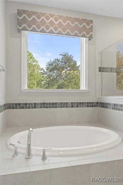 bathroom with a wealth of natural light and tiled bath