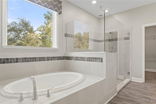 bathroom with hardwood / wood-style floors and shower with separate bathtub