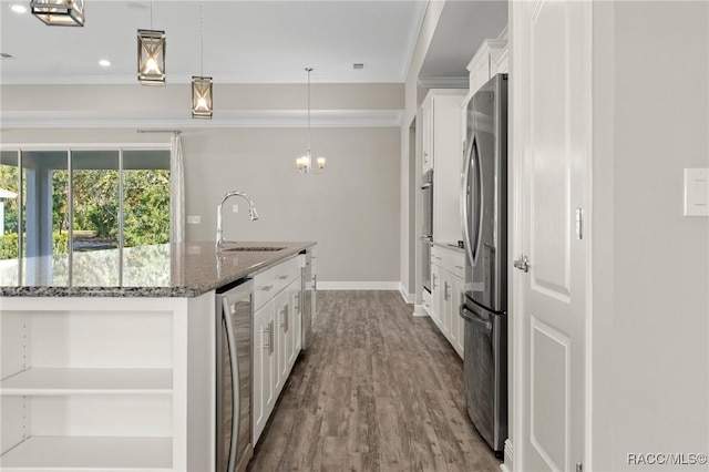 kitchen featuring white cabinetry, sink, an island with sink, pendant lighting, and dark stone counters