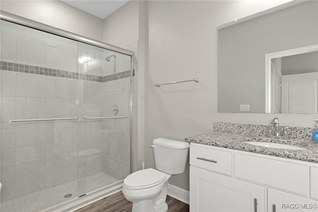 bathroom with hardwood / wood-style floors, vanity, toilet, and walk in shower