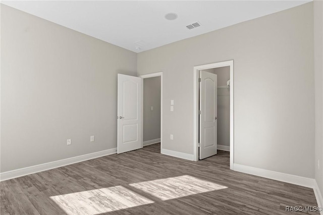 unfurnished bedroom featuring a spacious closet, a closet, and hardwood / wood-style flooring