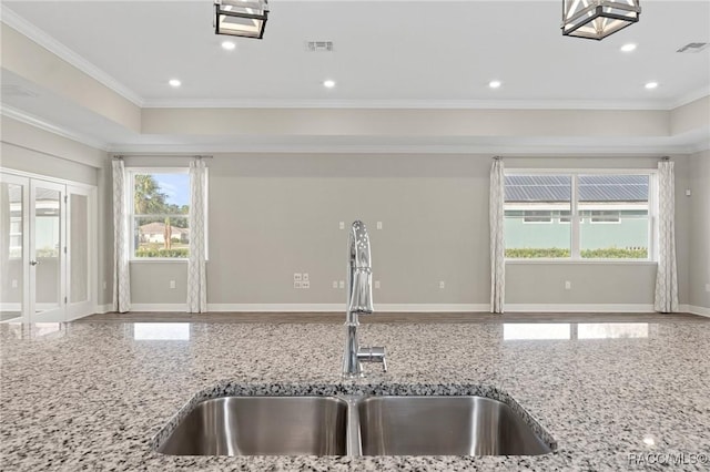 kitchen with light stone counters, crown molding, and sink