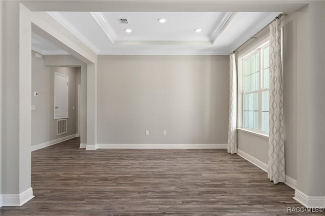 empty room with a tray ceiling, crown molding, and dark hardwood / wood-style floors