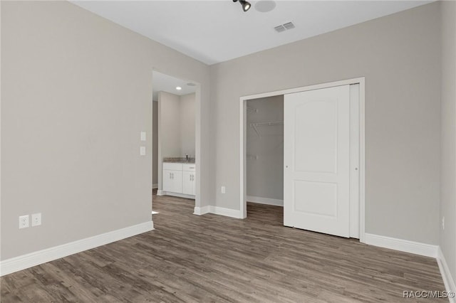 unfurnished bedroom featuring wood-type flooring, a closet, and sink