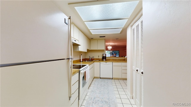 kitchen featuring white cabinetry, sink, light tile patterned flooring, and white appliances