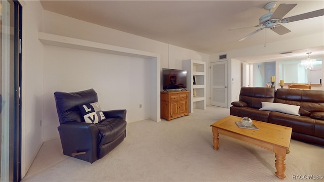 carpeted living room featuring ceiling fan with notable chandelier