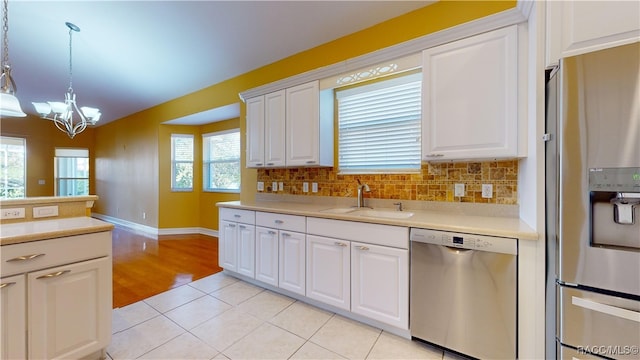 kitchen featuring appliances with stainless steel finishes, light tile patterned floors, sink, white cabinets, and pendant lighting