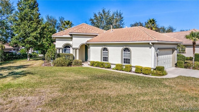 mediterranean / spanish house featuring a garage and a front yard