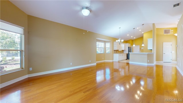 unfurnished living room featuring a chandelier, light hardwood / wood-style flooring, and high vaulted ceiling