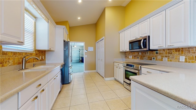 kitchen featuring decorative backsplash, sink, white cabinetry, and appliances with stainless steel finishes