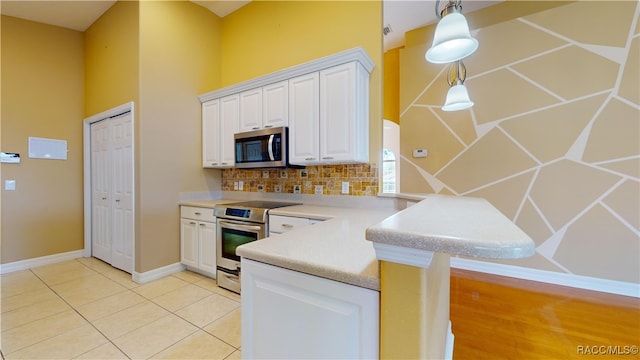 kitchen featuring tasteful backsplash, white cabinetry, kitchen peninsula, pendant lighting, and stainless steel appliances