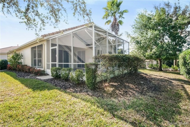 back of house with glass enclosure and a yard