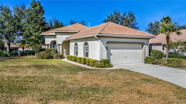 mediterranean / spanish house featuring a garage and a front yard