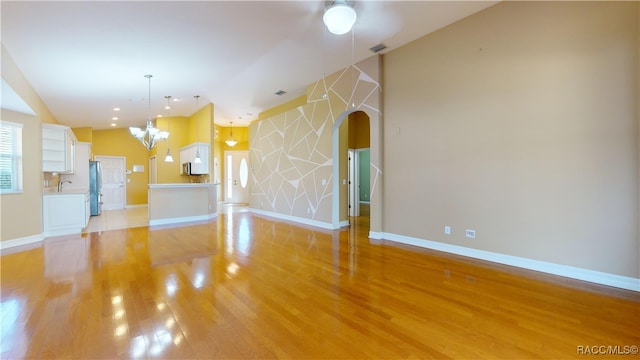 unfurnished living room featuring sink, a chandelier, and light wood-type flooring