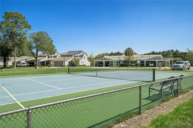 view of tennis court featuring a residential view and fence