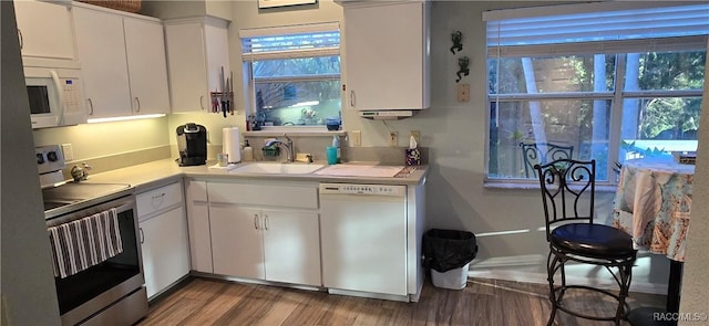 kitchen with light countertops, wood finished floors, white appliances, white cabinetry, and a sink