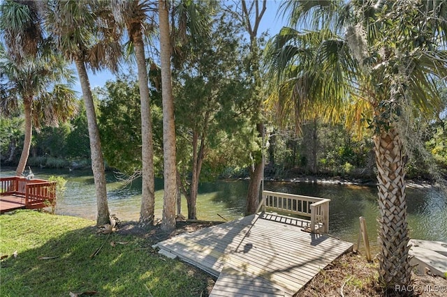 view of dock featuring a lawn and a deck with water view